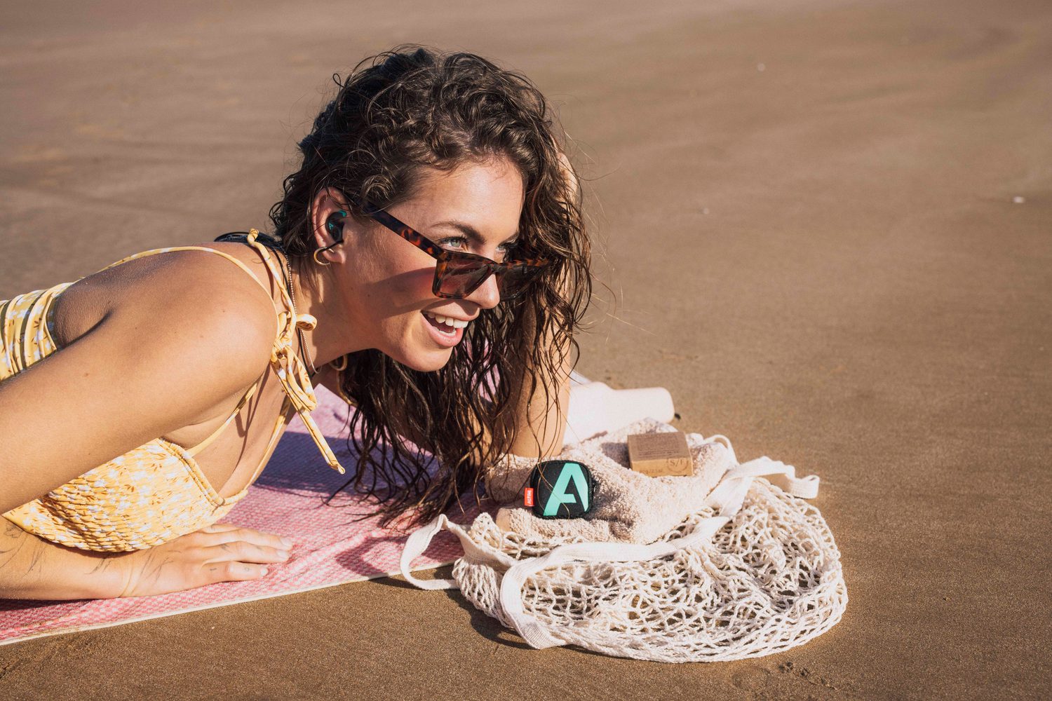 Woman lying on a towel with sunglasses and earplugs