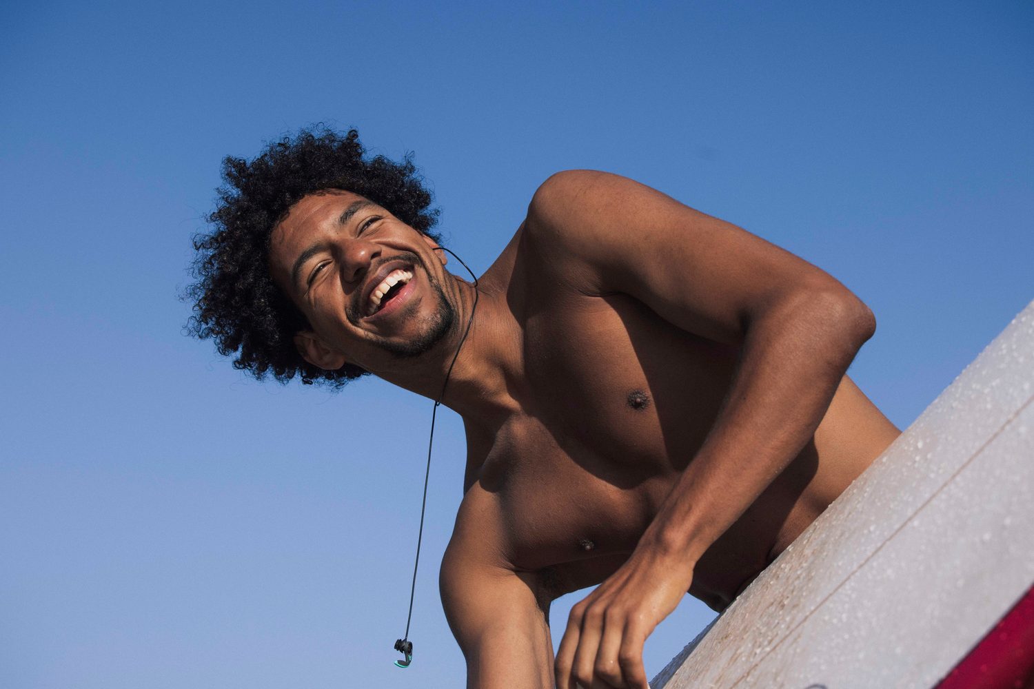 Laughing surfer leaning over his board