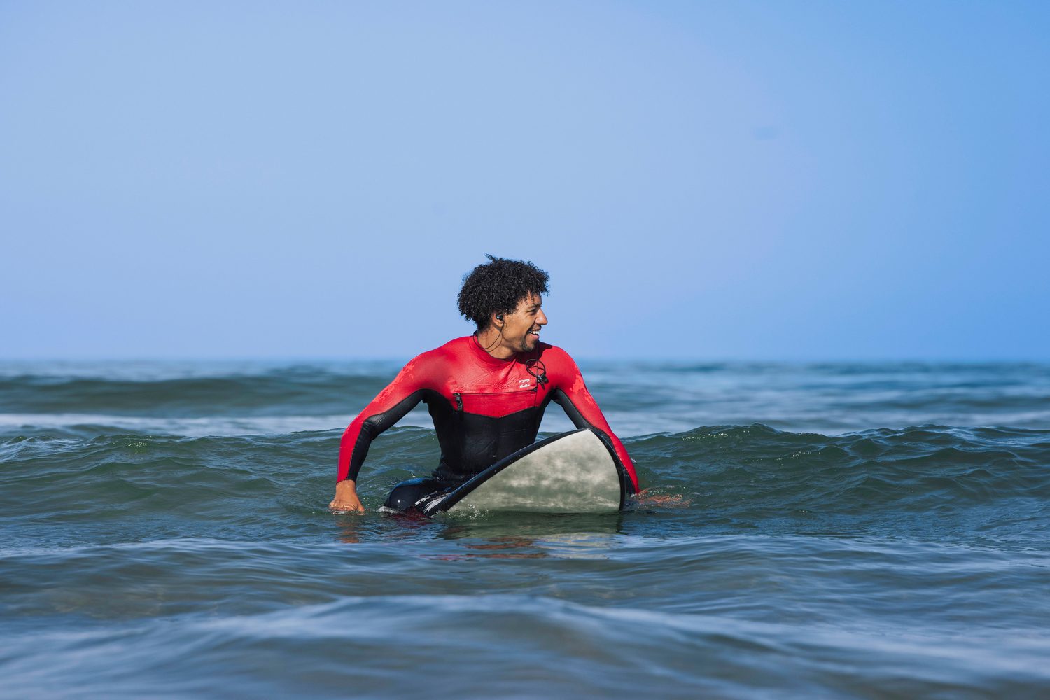 Surfer in a red wetsuit paddling out on his board