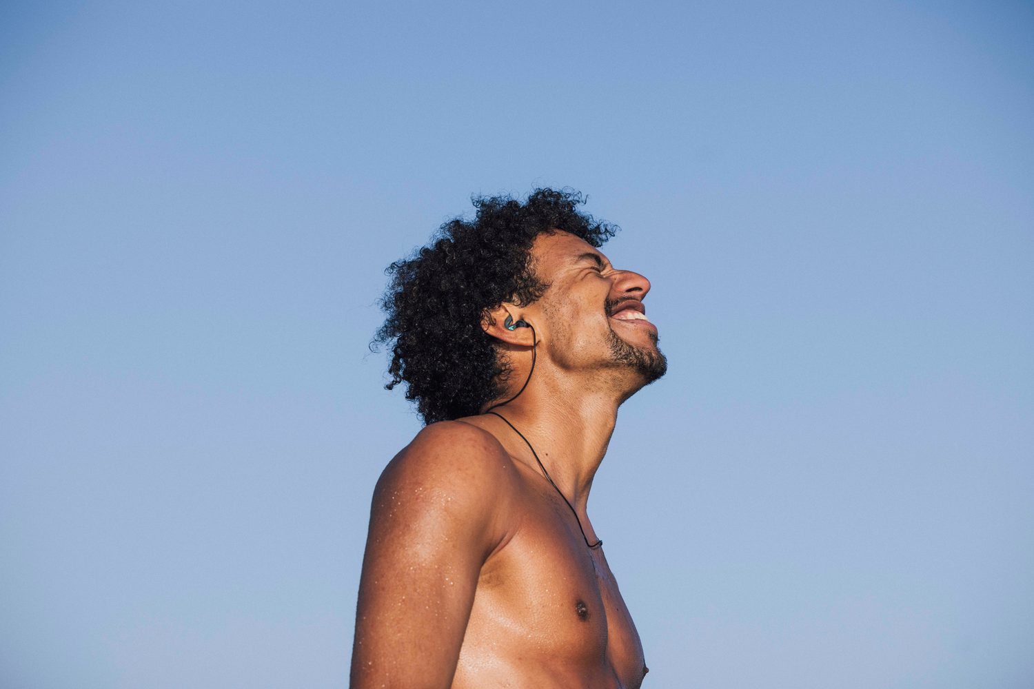 Surfer laughing with his head tilted back in the sun