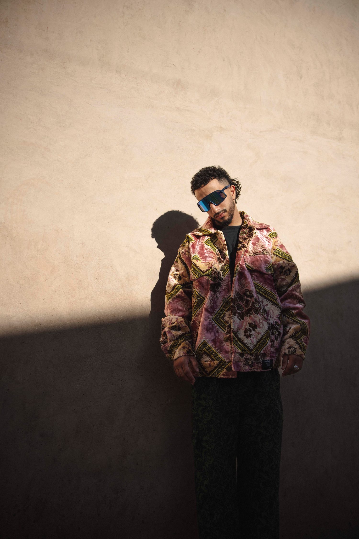 Model in a pink jacket half in shadow against a wall