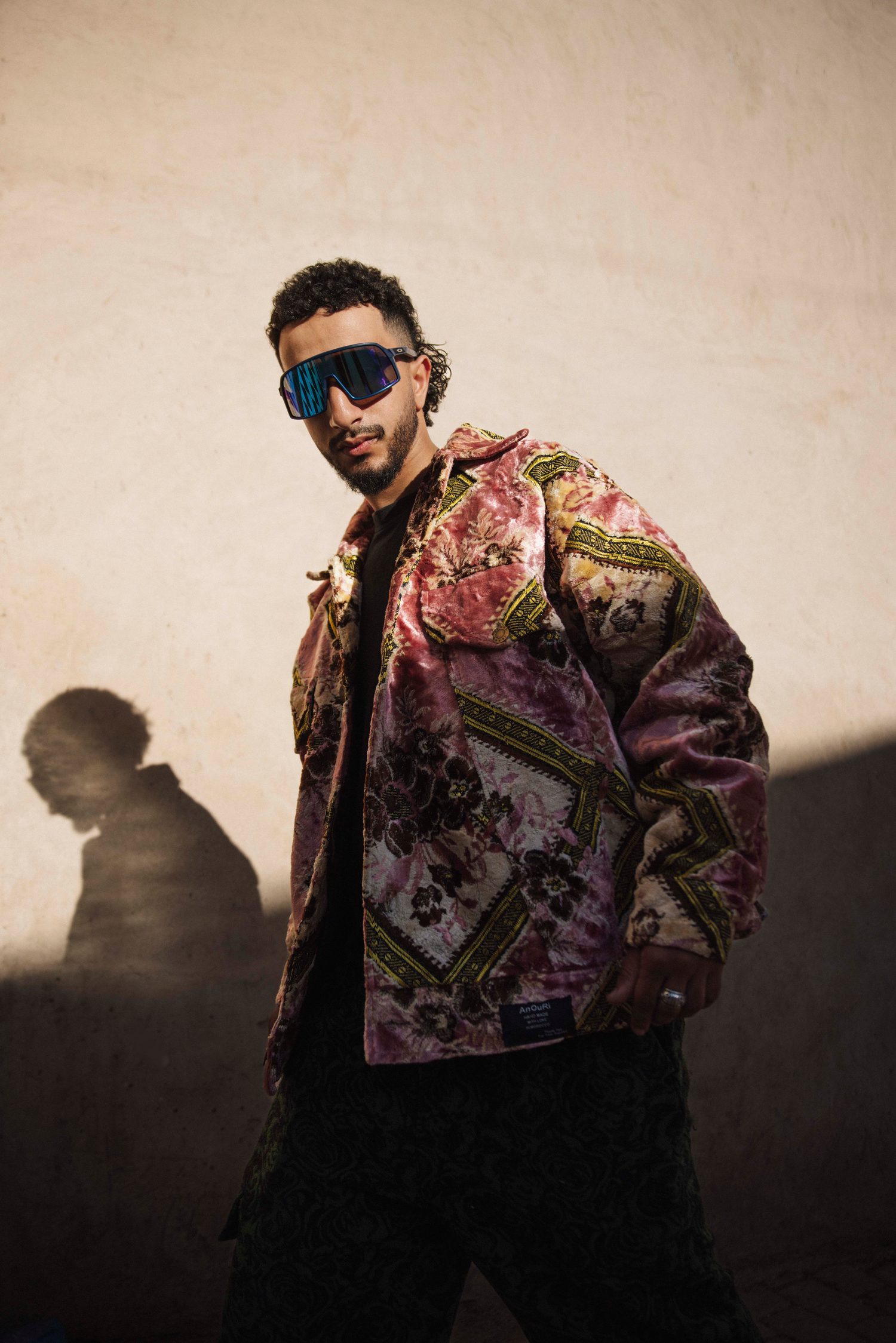 Model in a pink brocade jacket stepping out of the shadow
