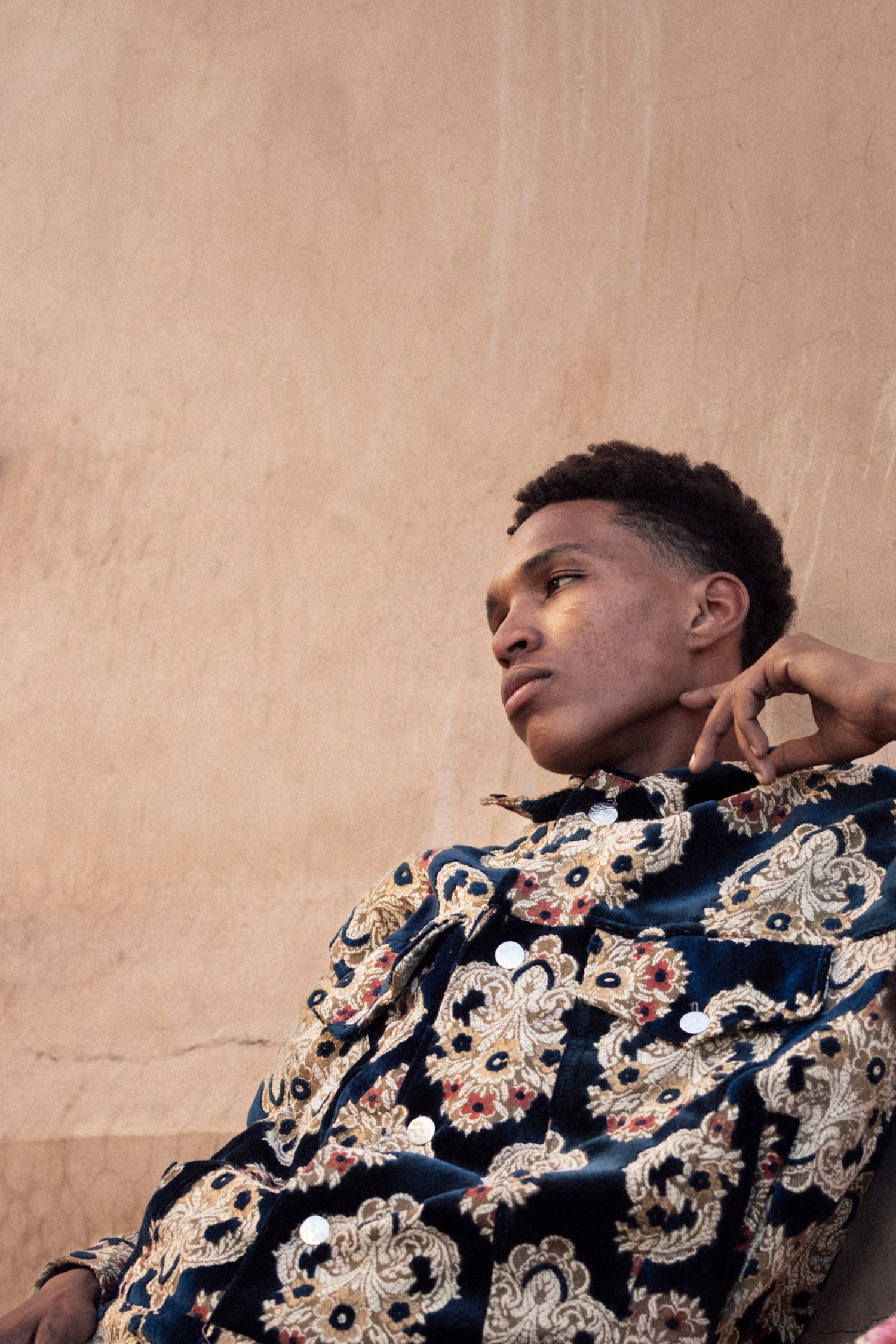 Model in an embroidered jacket looking away over his shoulder