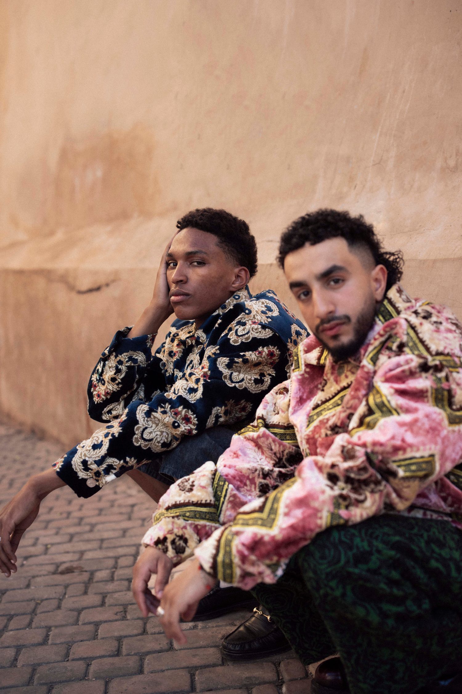 Two models crouching side by side in patterned jackets