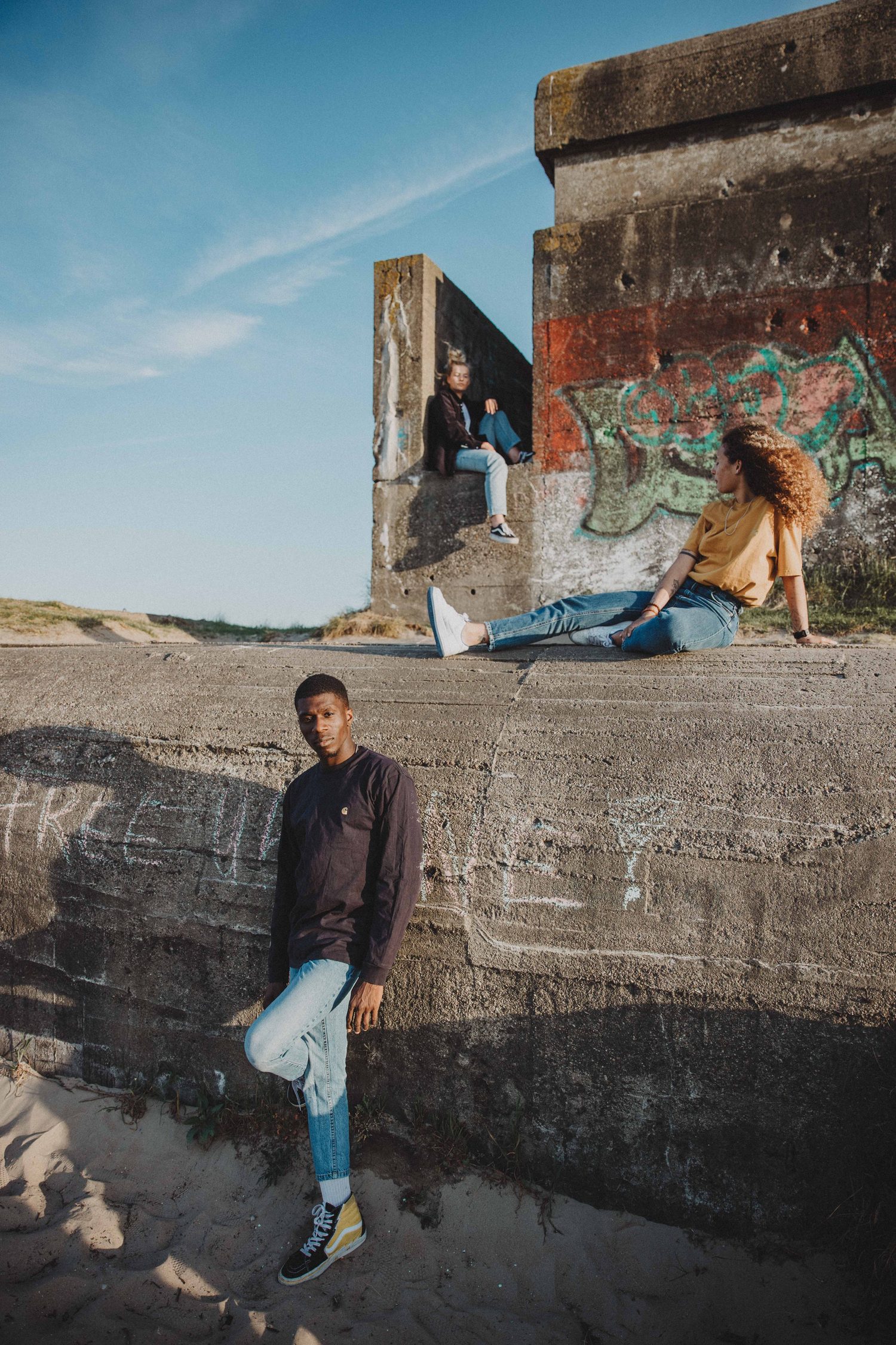 Models at a concrete bunker with graffiti on the beach