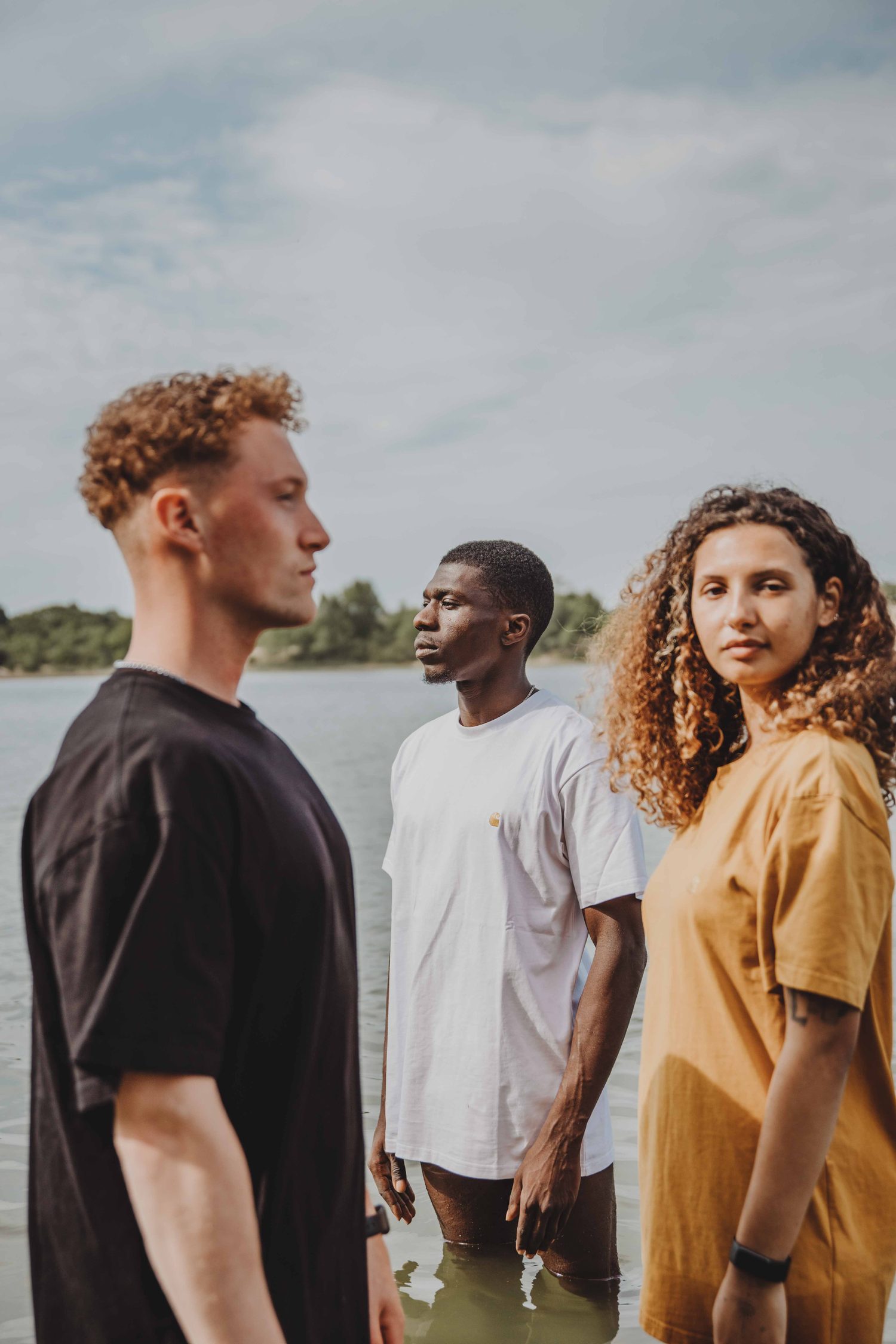 Three models in Carhartt T-shirts standing by the water