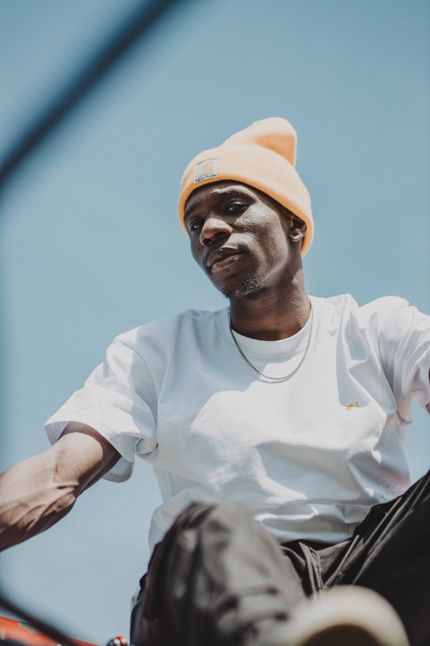 Low-angle portrait of a model in an orange beanie and white T-shirt
