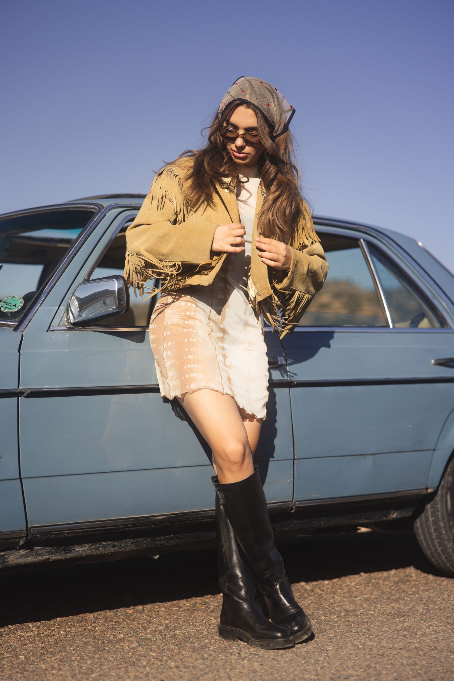 Woman in sunglasses leaning against a vintage blue Mercedes