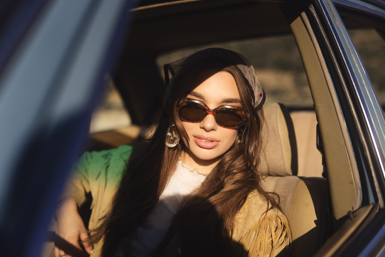 Woman in sunglasses at the wheel of a vintage car