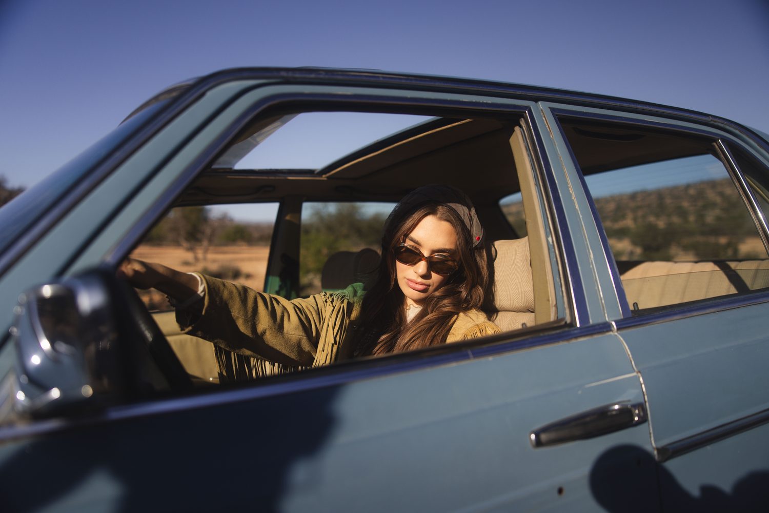 Woman leaning out of the window of a vintage blue car