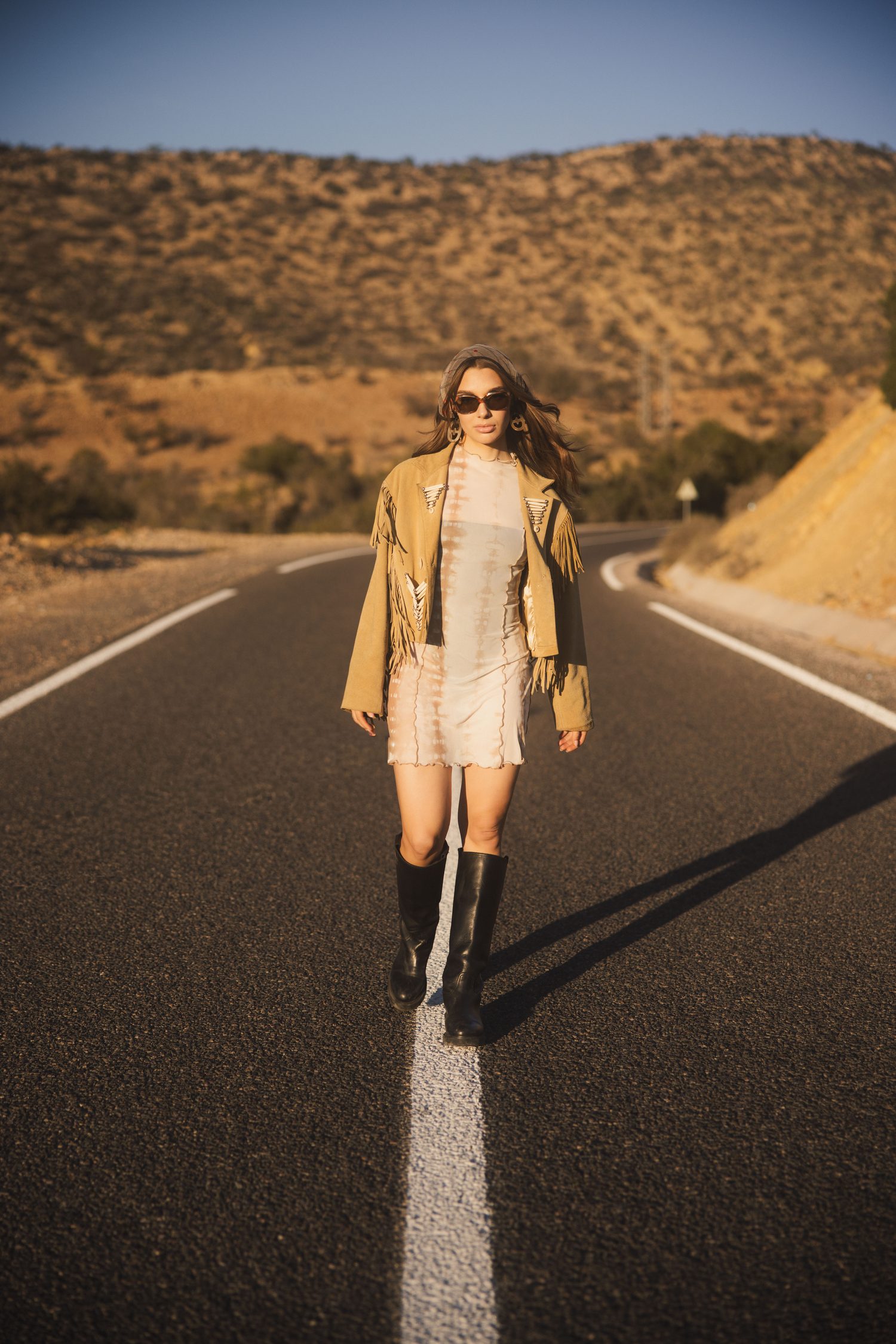 Woman walking down the centre line of a desert road