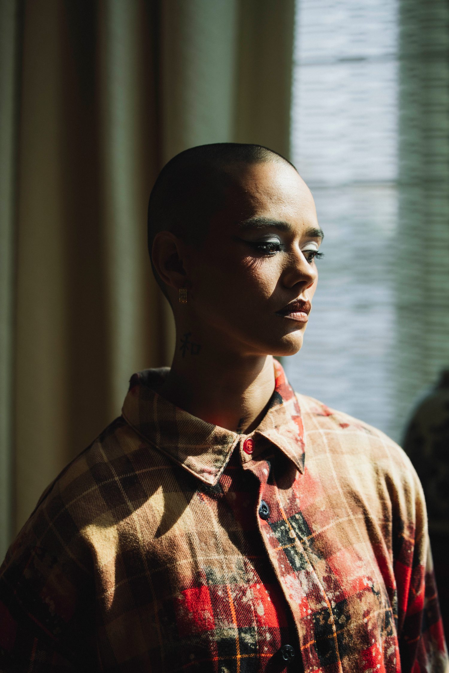 Model in a plaid shirt looking down in soft window light