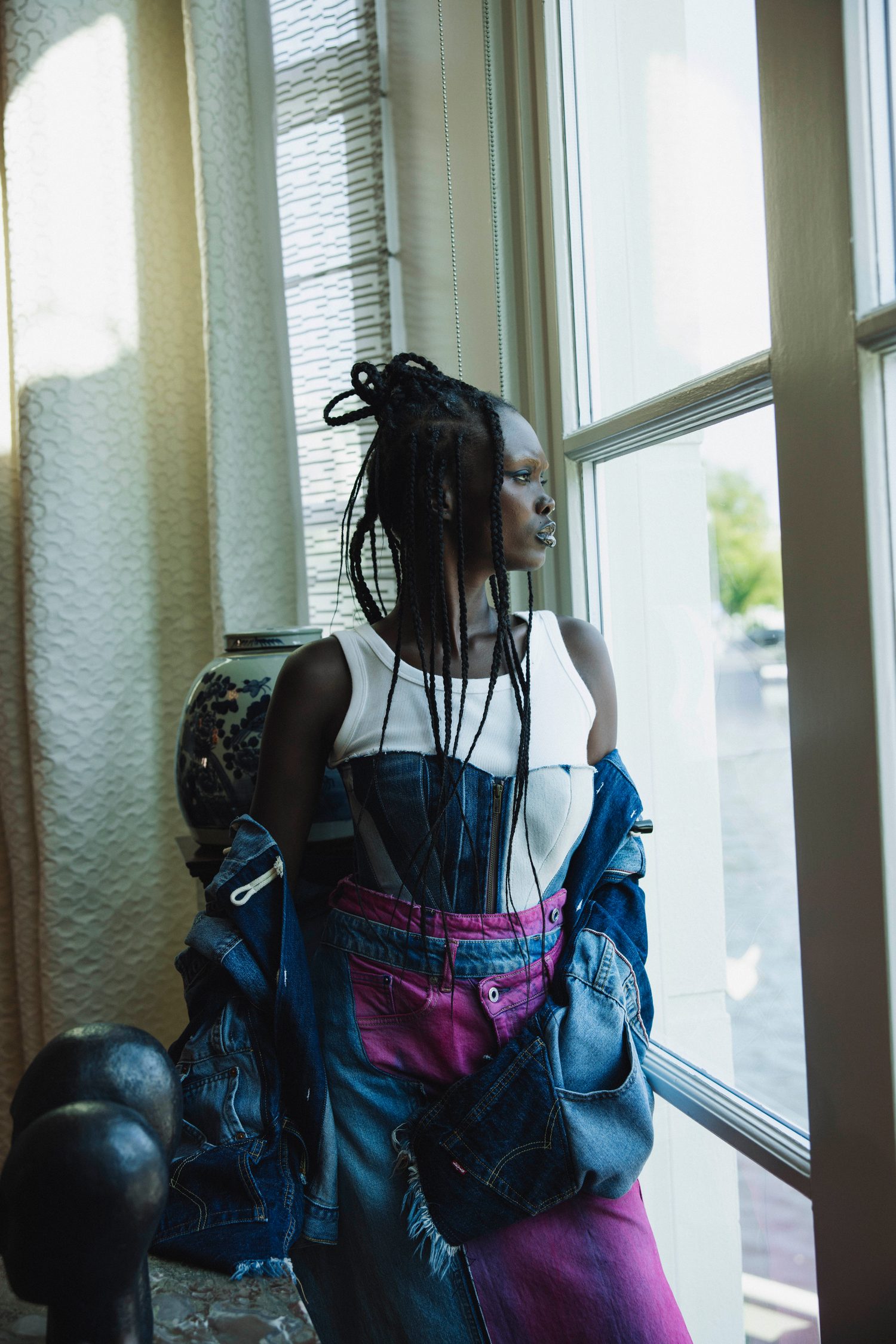 Model with long braids looking out of a sunlit window
